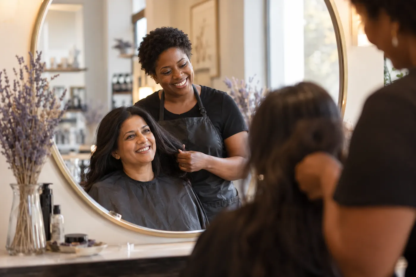 A hairdresser and her client chatting in the mirror of a calm salon.